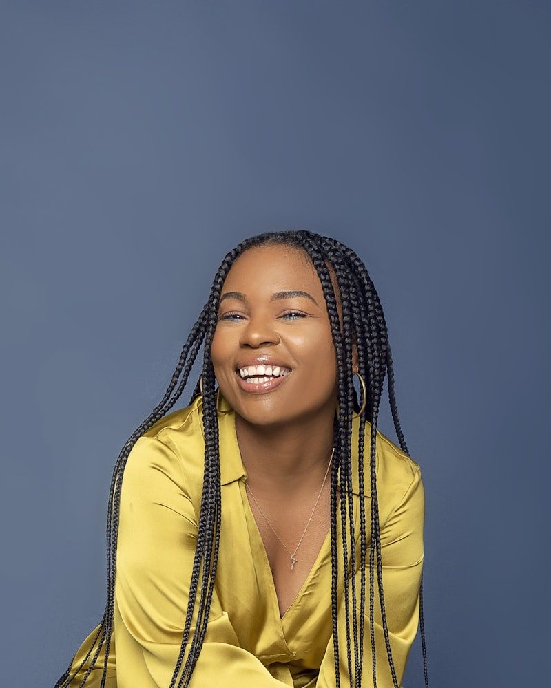 Knotless Braids, hüftlang, lachend vor blauem Hintergrund