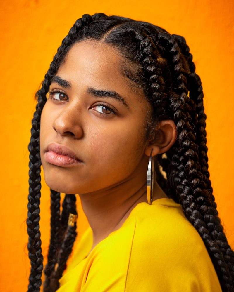 Feed-in Braids, brustlang, vor orangefarbenem Hintergrund